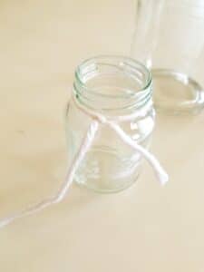 Tie a string around small jar in water density science experiment