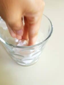 Push paper down into glass for this science experiment for homeschoolers.