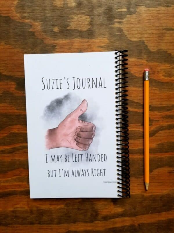 Custom left handed notebook comes with hand illustrated left hand thumbs up. Hand comes in light skin and dark skin tones. Customize the text on the title. This example shows it being used as a journal. Funny quote at the bottom of cover.