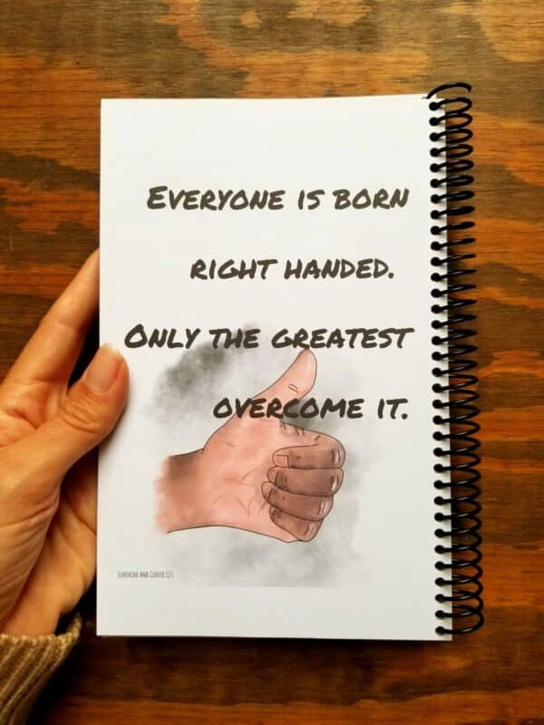 Notebook for lefties in marker style font is shown with the darker skin tone on the thumbs up hand. You can choose from 3 font styles and from light skin and dark skin tones.