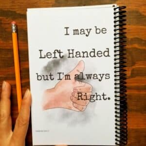 Notebook for left handers with spiral binding on opposite of normal side. Journal cover has hand illustrated thumbs up and a funny saying. Left handed journal cover is made from durable chip board.