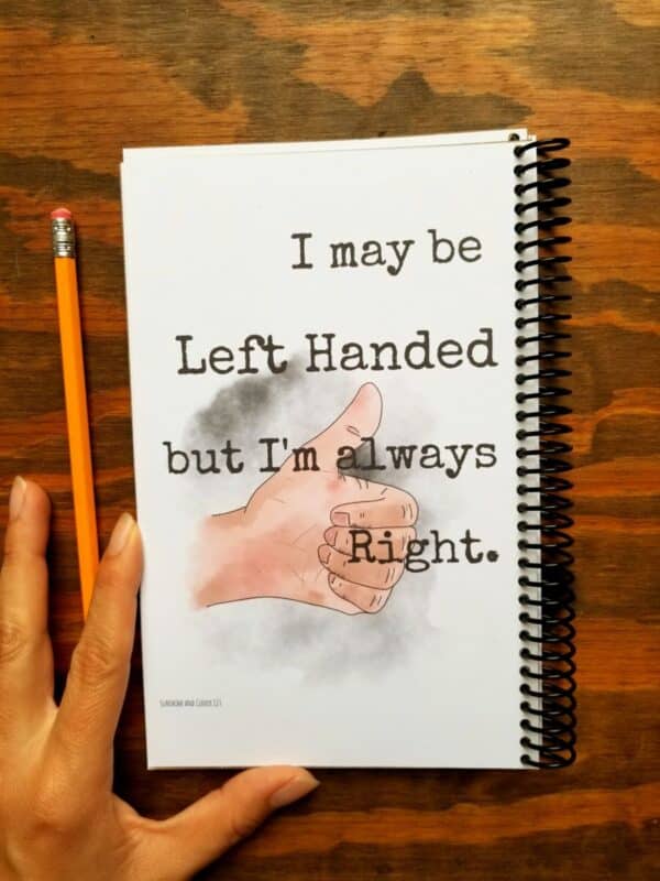 Notebook for left handers with spiral binding on opposite of normal side. Journal cover has hand illustrated thumbs up and a funny saying. Left handed journal cover is made from durable chip board.