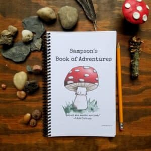 Spiral bound notebook with hand illustrated mushroom and customizable text and font. Notebook is half letter sized and has black spiral binding along the edge. White background on the cover with red mushroom and custom title and optional message or quote.