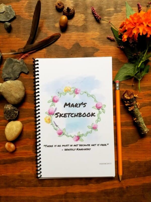Custom sketchbook with hand illustrated flower design on the cover encircling the title of your choosing. Customize the text and font of your notebook, including room for a message or quote.