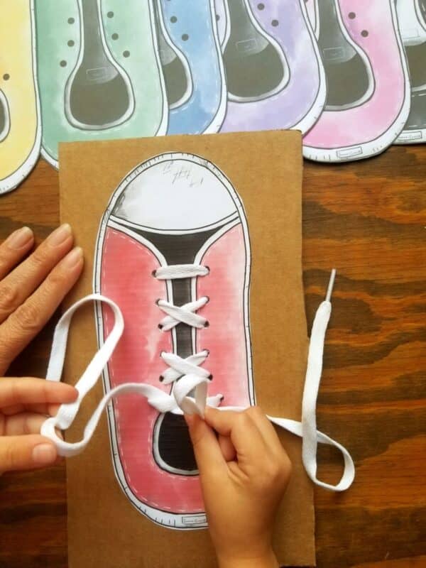 Sneaker lace board with red sneaker being tied by a young child. Glue your sneaker on cardboard to get a sturdy piece.