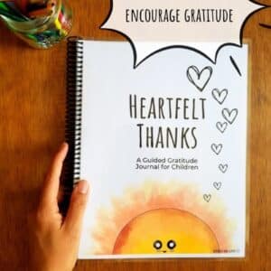Printable prompted journal with gratitude writing prompts. Cover has a smiling sunshine rising up from the bottom edge and is shown spiral bound for ease of use. Journal is titled heartfelt thanks.
