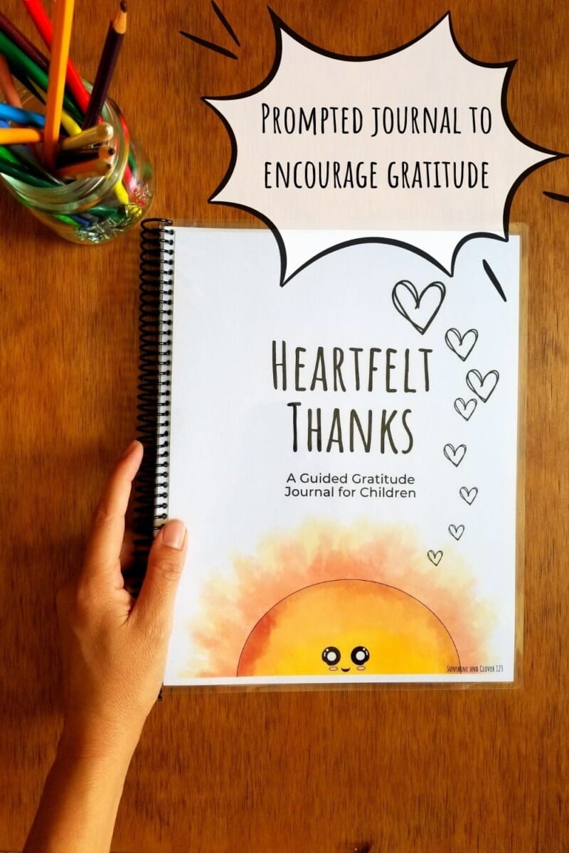 Printable prompted journal with gratitude writing prompts. Cover has a smiling sunshine rising up from the bottom edge and is shown spiral bound for ease of use. Journal is titled heartfelt thanks.