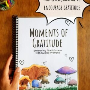 Prompted journal for gratitude comes with hand illustrated front cover. Journal features colorful mushrooms on the front cover with little playful hearts and is titled Moments of Gratitude.